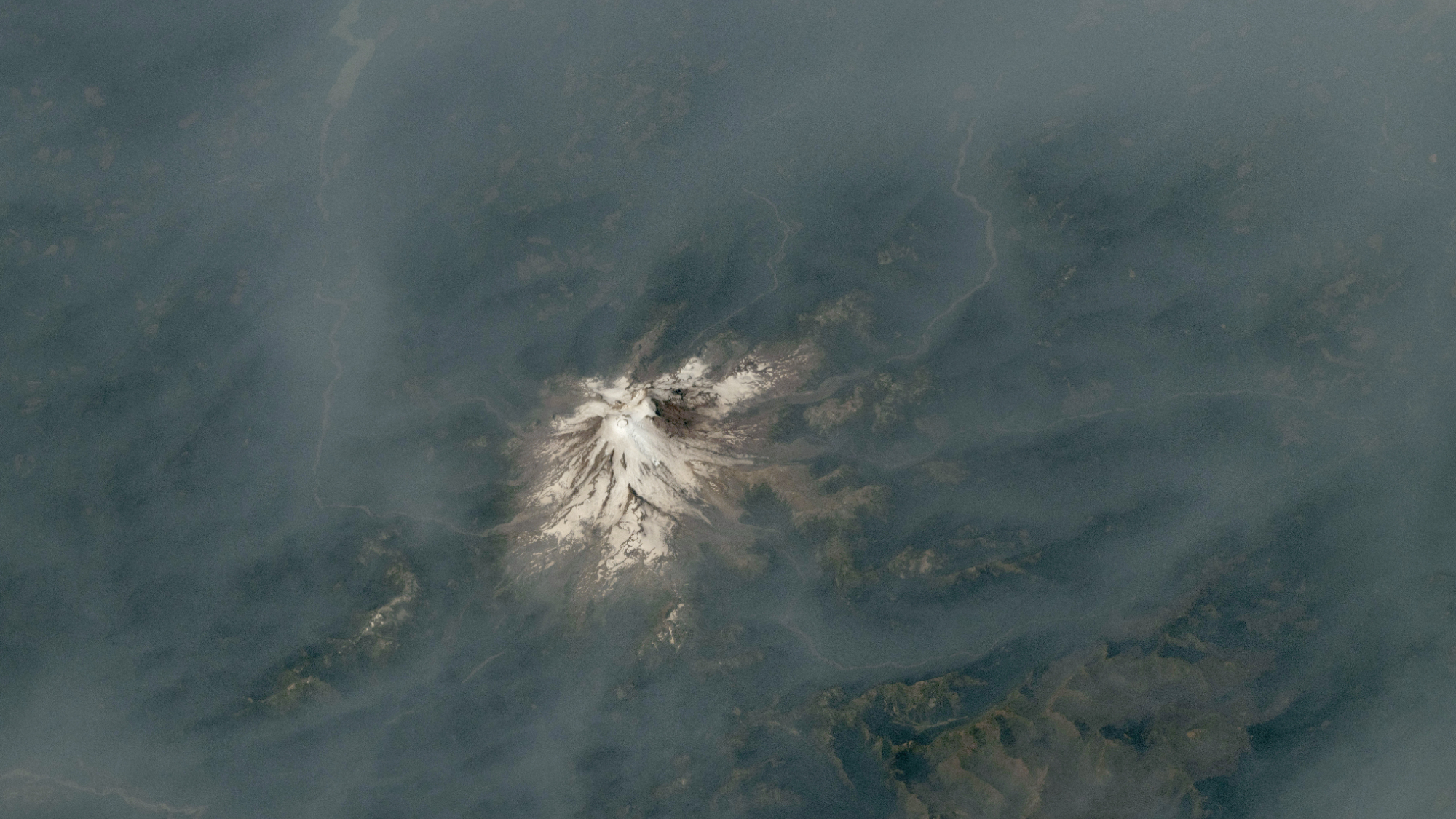 A volcano emerging from a blanket of smoke.