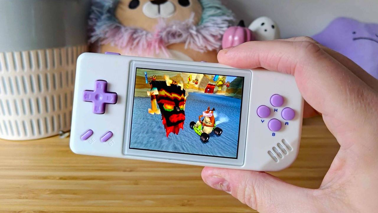 Hand holding Anbernic RG28XX handheld with Crash Team Racing PS1 gameplay on screen.