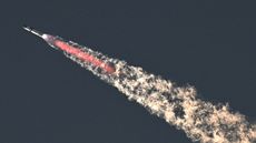 Photo of starship flying through the sky with a plume of fire and smoke