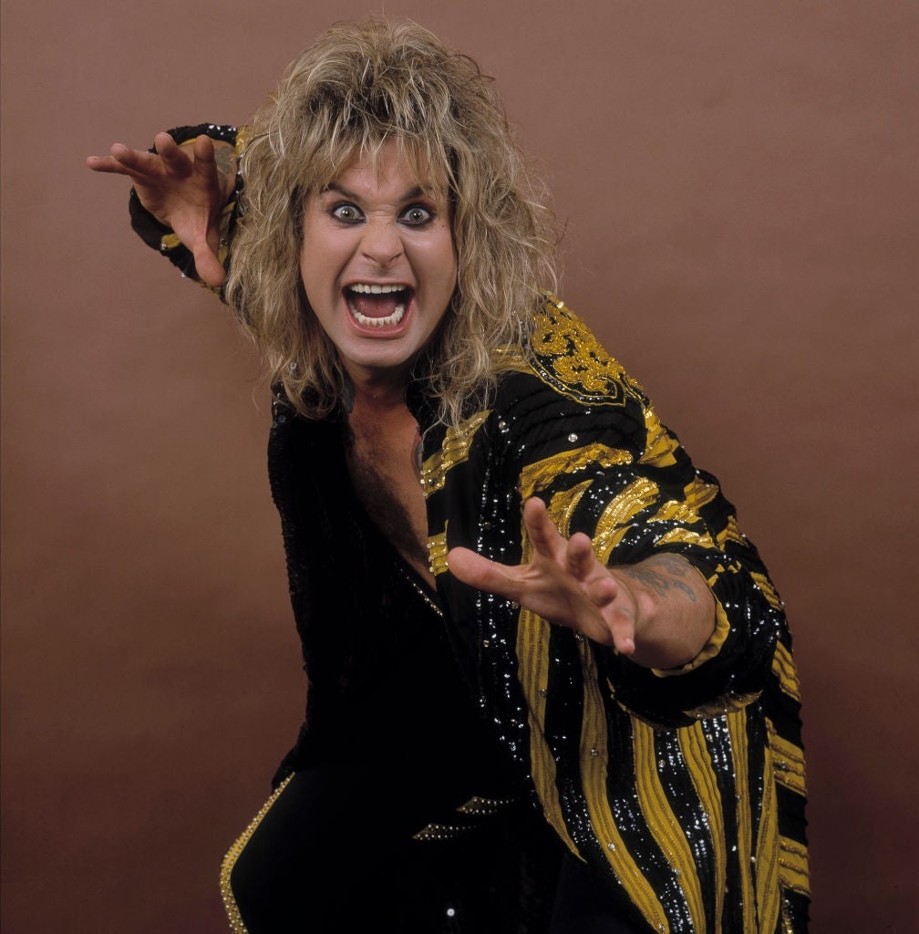 Person with long hair and expressive pose wearing a patterned robe with bold detailing, giving an energetic, playful performance appearance