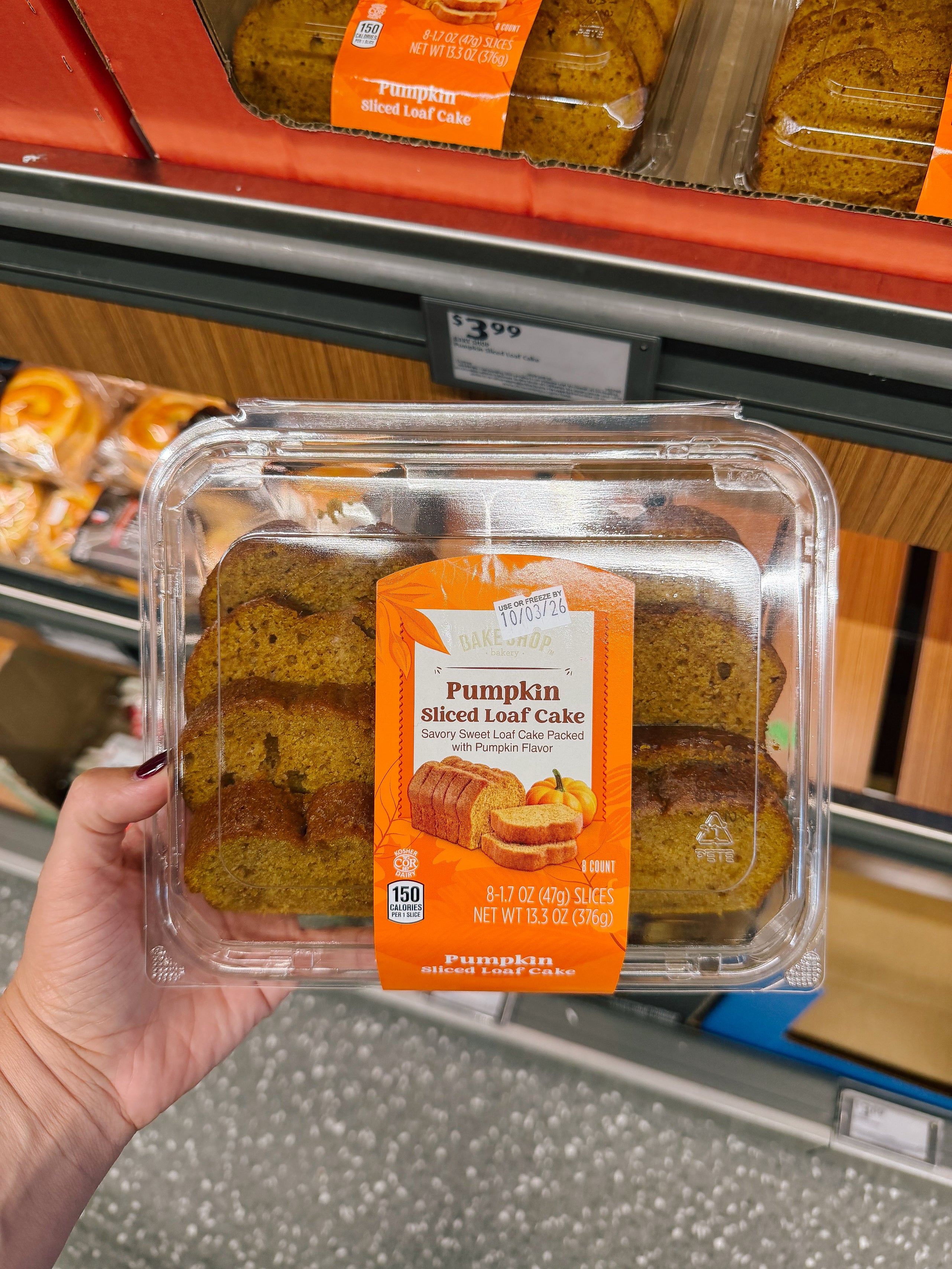 Person holding a packaged pumpkin sliced loaf cake in a store