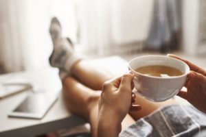 Chronotypes: Definition, Types, & Effect on Sleep person sitting at desk with cup of coffee